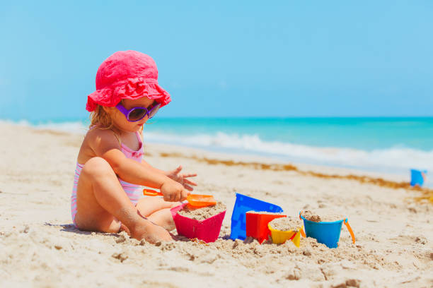 istock cute little girl play with sand on beach 690035542