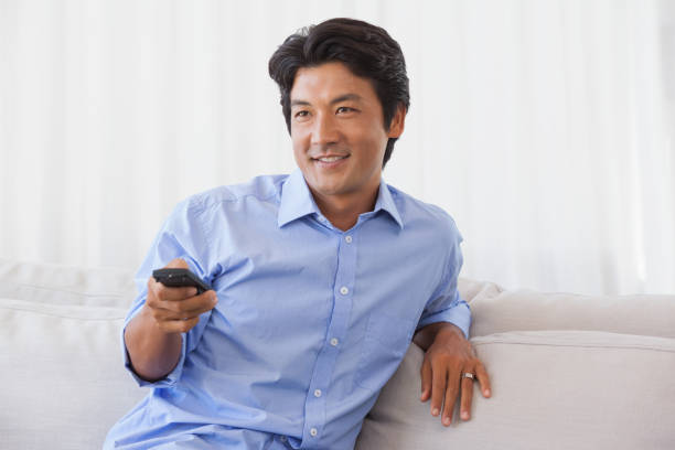 istock Happy man sitting on couch watching tv 690035606