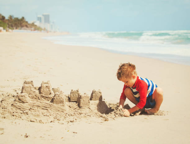 istock little boy play with sand on beach 690036080