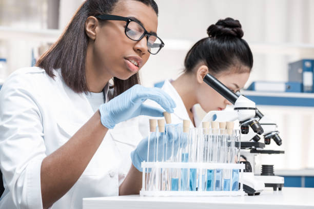 Professional young scientists working with microscope and test tubes in chemical laboratory Professional young scientists working with microscope and test tubes in chemical laboratory african american scientist stock pictures, royalty-free photos & images