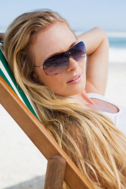 istock Gorgeous blonde in sunglasses sitting at the beach 690039360