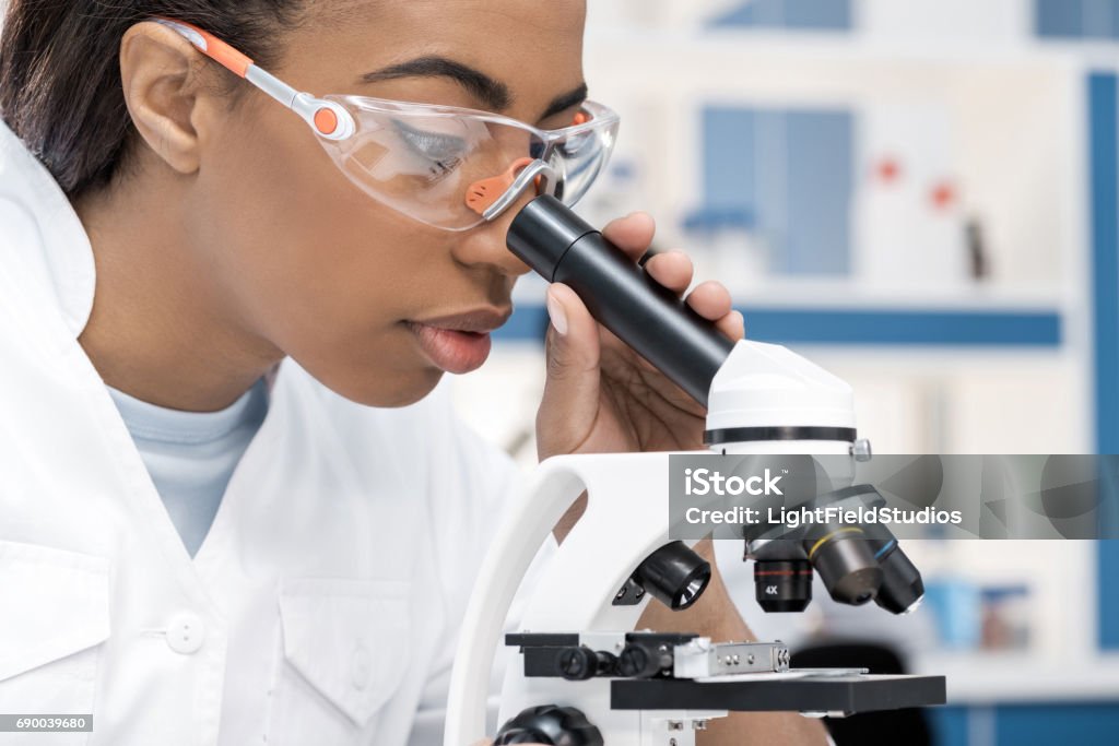 concentrated african american scientist in lab coat working with microscope in chemical lab Scientist Stock Photo