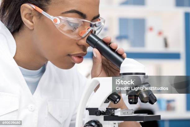 Concentrated African American Scientist In Lab Coat Working With Microscope In Chemical Lab Stock Photo - Download Image Now