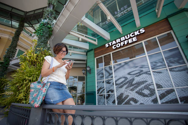 11 月 - タイのバンコク 16,2014: socialmedia starbcks コーヒー スターバックスのコーヒー ショップの前でチャットに接続するタイの女性で最も人気のあるタイ - starbucks coffee coffee shop women ストックフォトと画像
