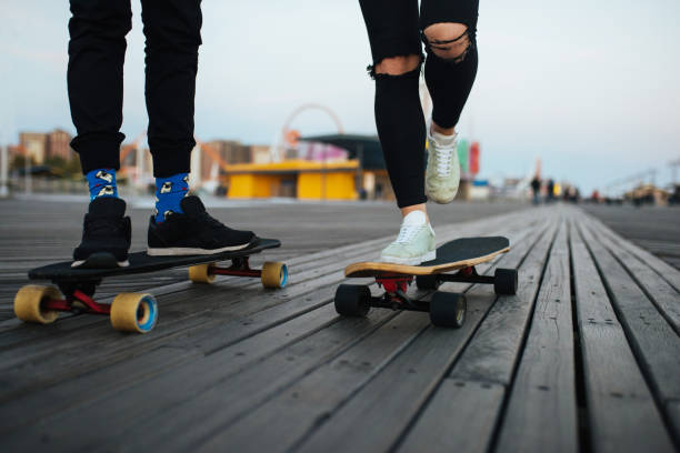 istock Couple riding longboards on the boardwalk, feet only 690047406