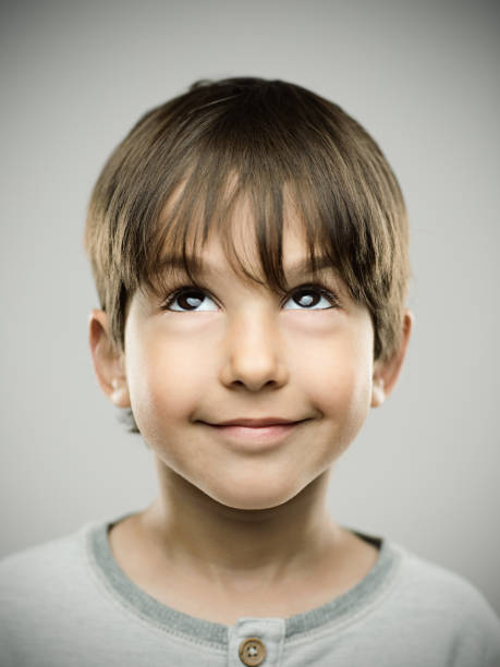 istock Little boy looking up on gray background 690053870