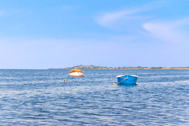 траулер и гребная лодка на якоре перед островом - buoy anchored sea wave стоковые фото и изображения
