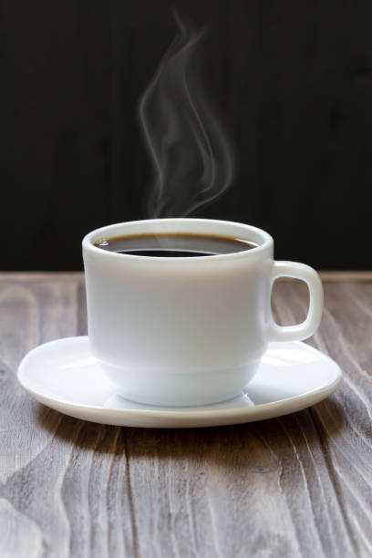 istock White cup of coffee on wooden surface on dark background 690064052