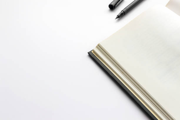 istock office workplace with text space, open black book on white table with soft-focus and over light in the background 690064998