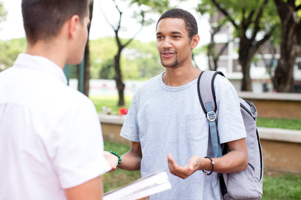 istock Smiling young student man taking to friend outdoor 690066636