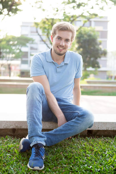 istock Smiling guy resting from bustle of city in park 690076746