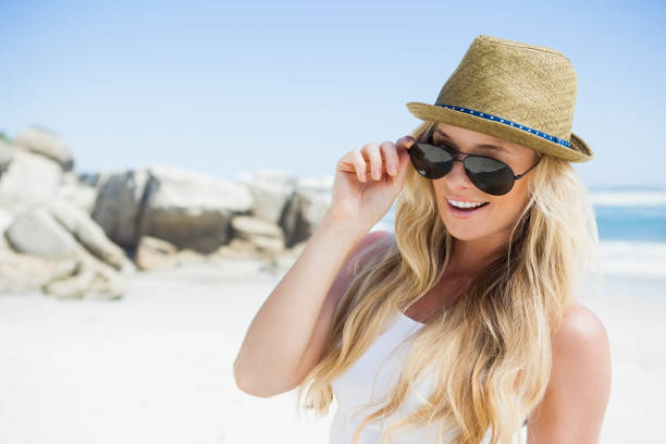 istock Stylish blonde smiling at camera on the beach 690080386