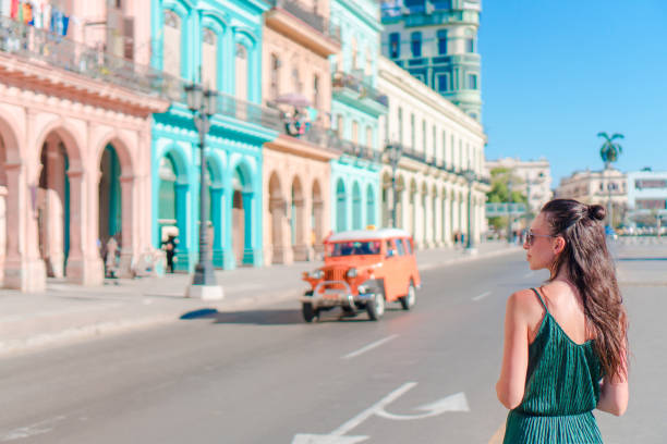 szczęśliwa kobieta w popularnej okolicy w starej hawanie, kuba. młoda dziewczyna podróżniczka tło kolorowe domy - cuba cuban culture car collectors car zdjęcia i obrazy z banku zdjęć