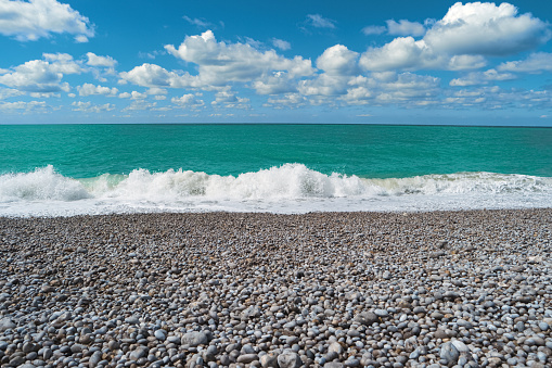 Beach, blue sea, cloudy sky. Beautiful landscape. Scenic view of ocean, wave, stones on sunny summer day. Seascape, pebble beach, Etretat, Normandy, France, Europe. Popular landmark famous destination