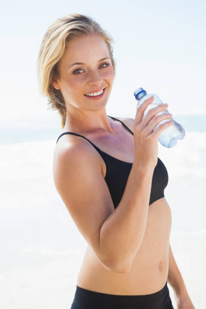 istock Fit blonde drinking water on the beach 690130794