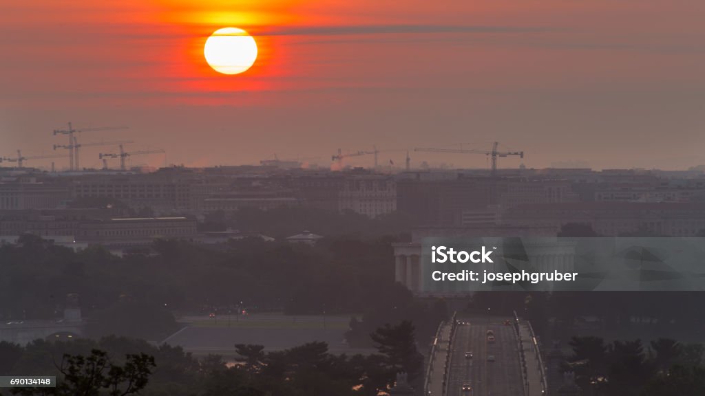 Bright sun on the horizon over the Washington, D.C. skyline The sun rises over the monuments, memorials, and construction cranes in Washington, D.C. Bridge - Built Structure Stock Photo