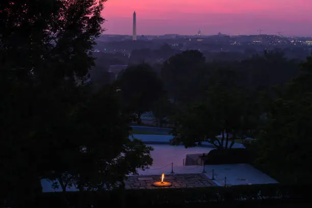 The sky over the Washington, D.C. skyline shows shades of pink and purple prior to sunrise from the John F. Kennedy eternal flame and presidential memorial in Arlington National Cemetery