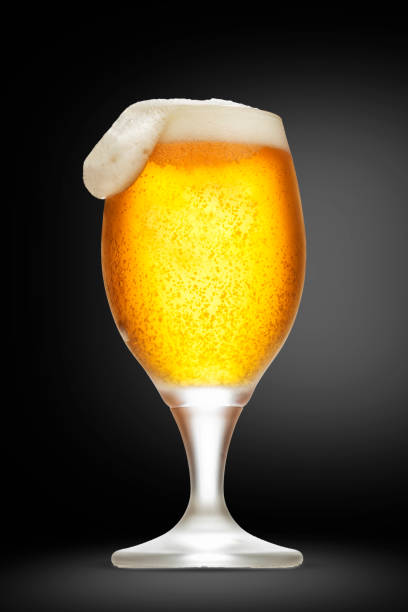 istock Glass of beer with foam falling to the left side isolated on black background 690135430