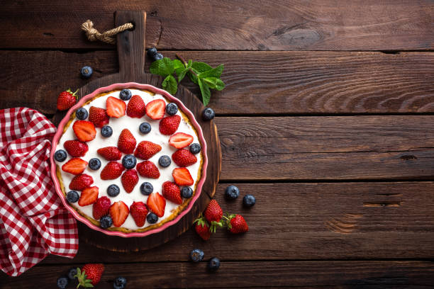 вкусный клубничный пирог со свежей черникой и взбитыми сливками на деревянном деревенском столе, чизкейк, вид сверху - strawberry tart стоковые фото и изображения