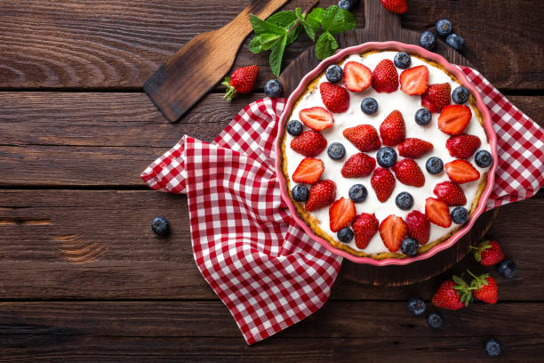 köstliche erdbeer torte mit frischen blaubeeren und schlagsahne auf rustikalen holztisch, käsekuchen, ansicht von oben - strawberry tart stock-fotos und bilder