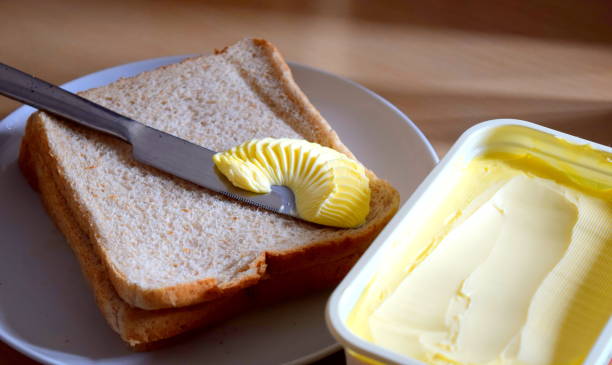 spargendo burro di margarina sul pane - spread foto e immagini stock