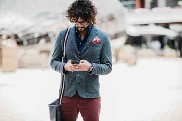 Curly-haired businessman using smartphone in the urban environment