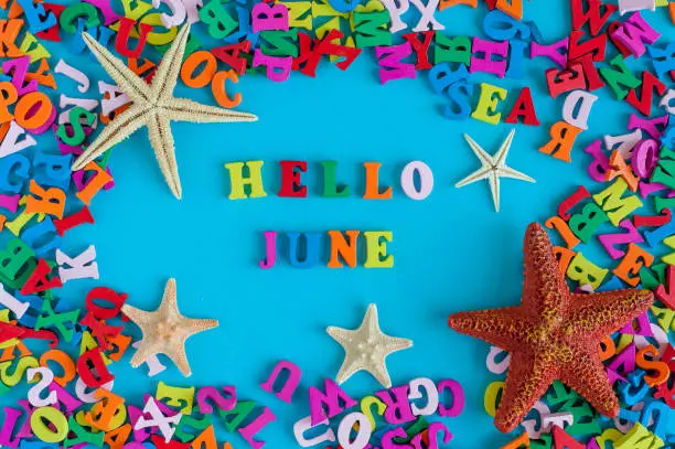 Photo of Hello June - word composed of small colored letters at blue background with beach attribute - starfish or five-finger. Summerbeginning and vacation concept