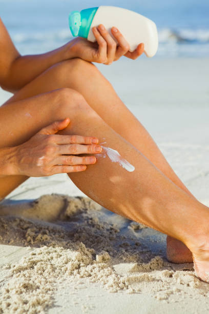 istock Woman sitting on the beach applying suncream 690167064