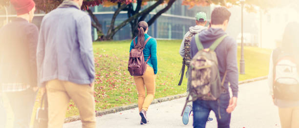 istock Rear view of sudents walking through the park 690169384