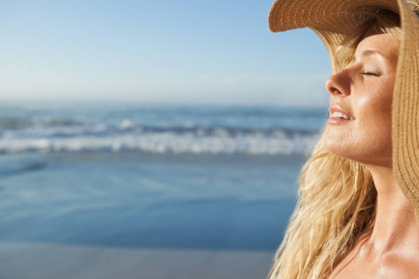 istock Gorgeous blonde in straw hat smiling on beach 690169620