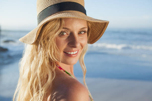 istock Gorgeous blonde in straw hat smiling on beach 690169642