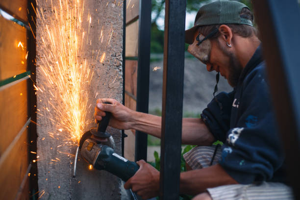istock Man with a grinder is building a fence. Sparks from angle grinder. 690177294