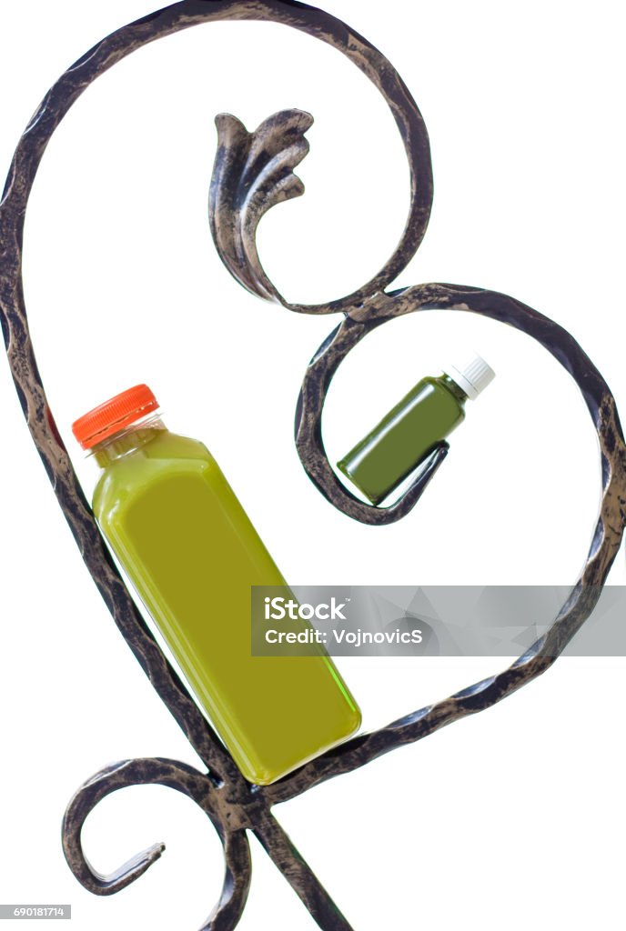 Green juice in bottle leaning on iron hearth frame, small and big White background Bottle Stock Photo
