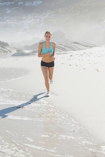 istock Fit woman jogging on the beach smiling at camera 690183626
