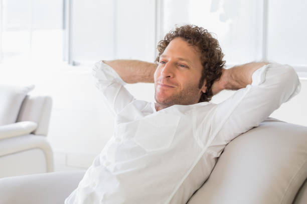 istock Relaxed man sitting with hands behind head at home 690190924