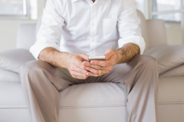 istock Mid section of a well dressed man text messaging at home 690191080