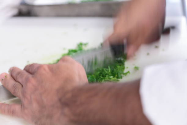 Kitchen action. Chef is chopping parsley.
