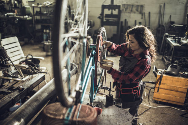 Repairing her bike One woman, repairing her bicycle, working in workshop bike workshop stock pictures, royalty-free photos & images