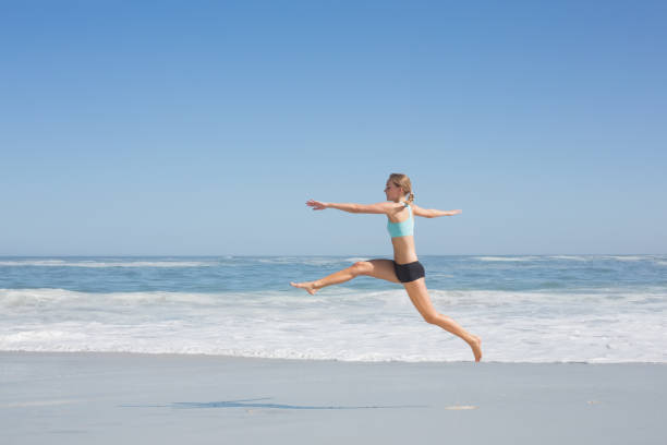 istock Fit woman jumping gracefully on the beach 690194600