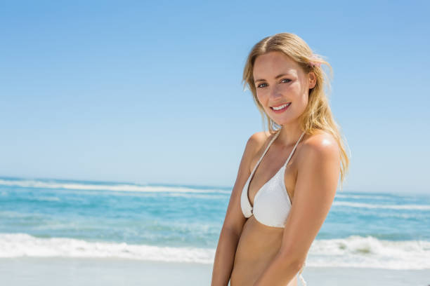 istock Beautiful blonde in white bikini smiling at camera on the beach 690206320