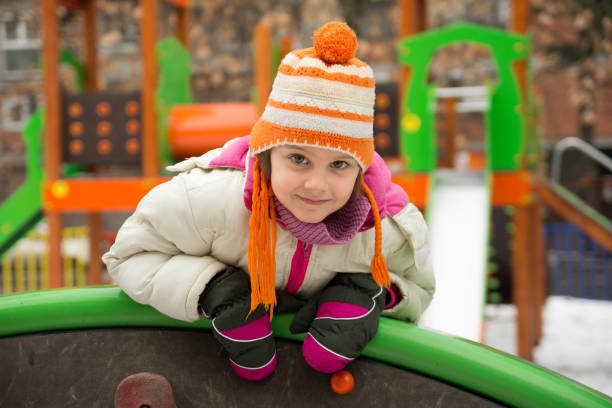 Little girl having fun in winter playground .