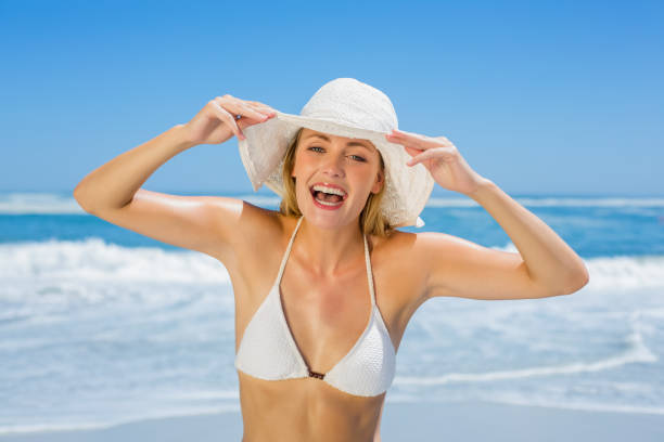 istock Smiling blonde in white bikini and sunhat on the beach 690214992