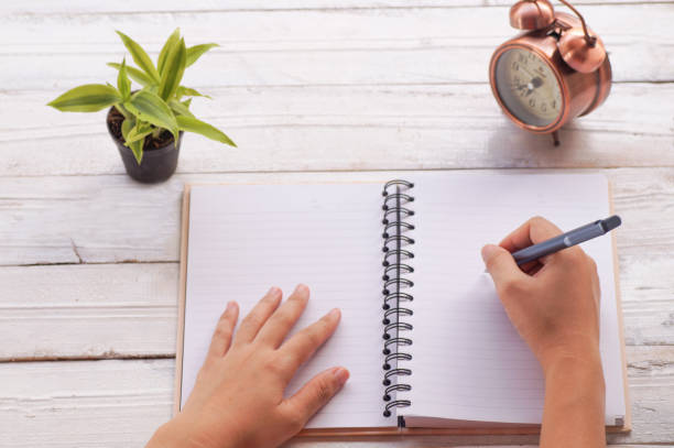 istock hand writing with books  and clock  on desk 690218212