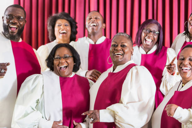 Mature black women and men singing in church choir A group of mature African American women and men wearing robes, singing in a church choir. black female gospel singers stock pictures, royalty-free photos & images