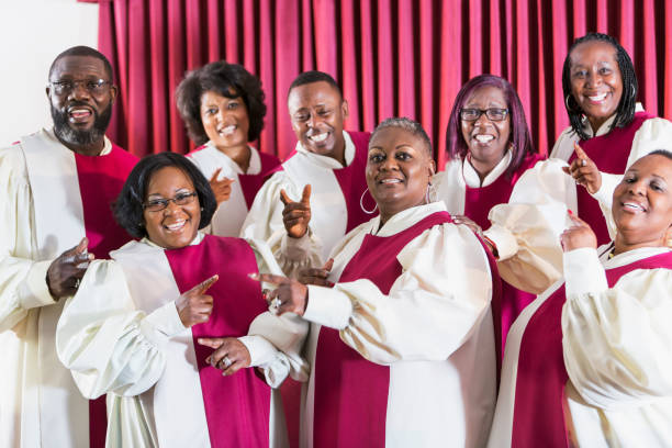 Mature black women and men singing in church choir A group of mature African American women and men wearing robes, singing in a church choir. black female gospel singers stock pictures, royalty-free photos & images