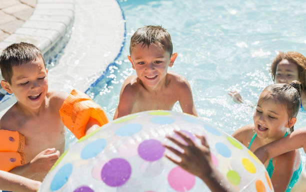 enfants multiethniques avec ballon de plage géant dans la piscine - beach ball swimming pool ball child photos et images de collection