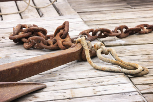 Rusted chain links, weathered rope and a ship's anchor lay on the wooden deck of an old commercial fishing trawler.