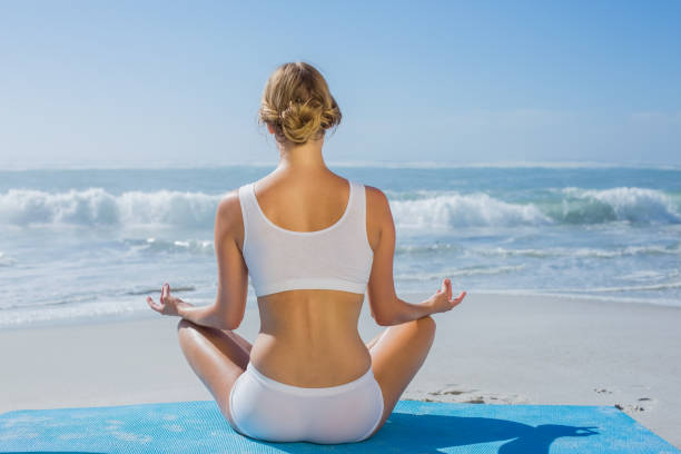 istock Fit woman sitting in lotus pose on the beach 690224268