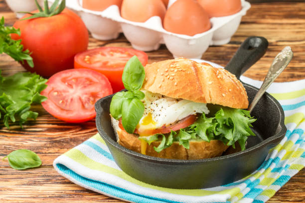 istock Breakfast. Bun with sesame seeds, poached egg,  tomato and greens. Selective focus 690228980