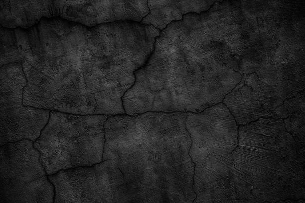 istock Black concrete wall covered with cracks. Gloomy surface of the cement board 690240308